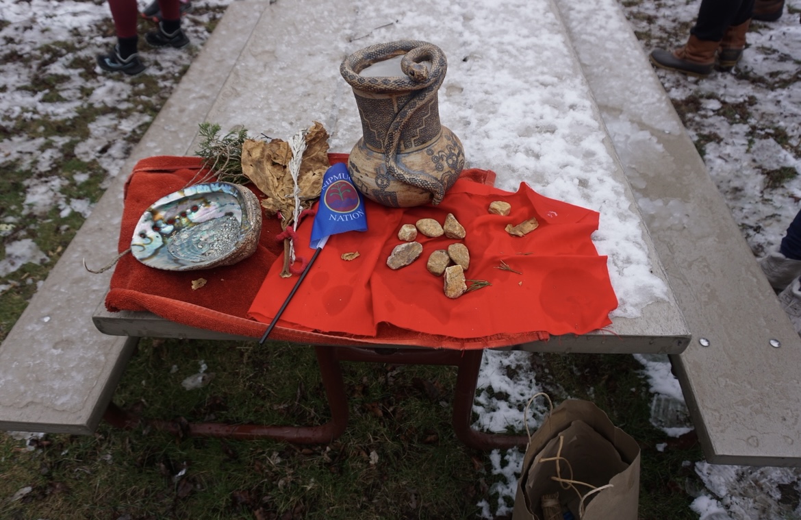 Ceremonial items laid out on a table, including an abalone shell, sage, and a Nipmuc Nation flag