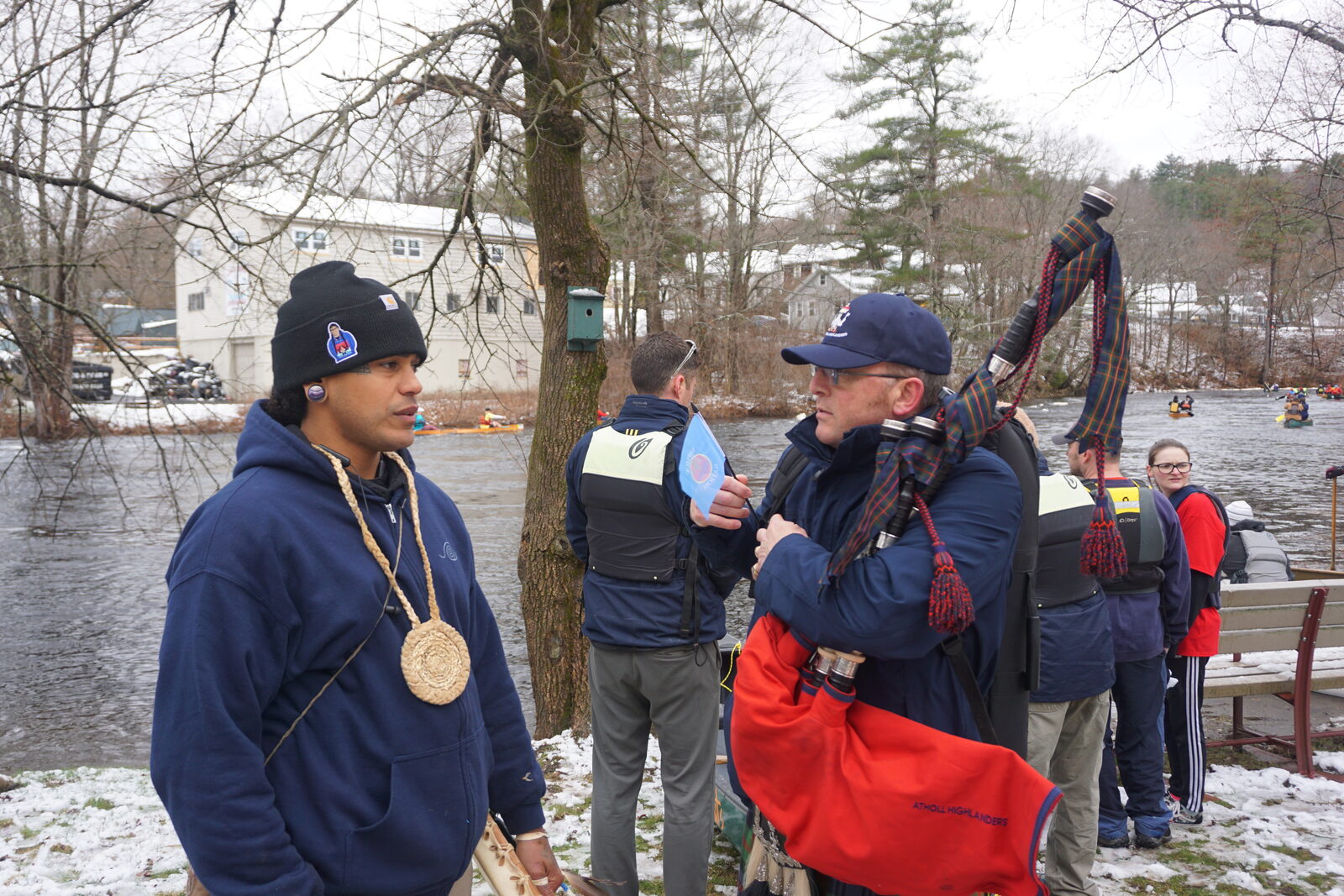 A community member speaking with bagpipers gathered by the river before the race