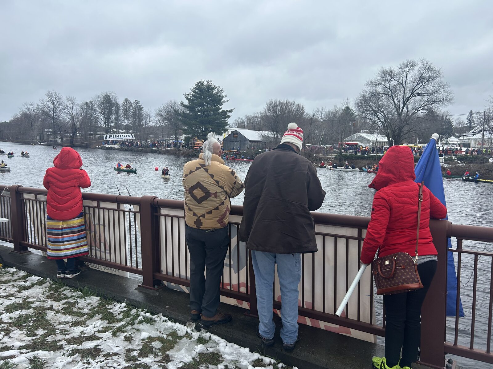 Community members watching the canoe race from a bridge overlooking the finish line