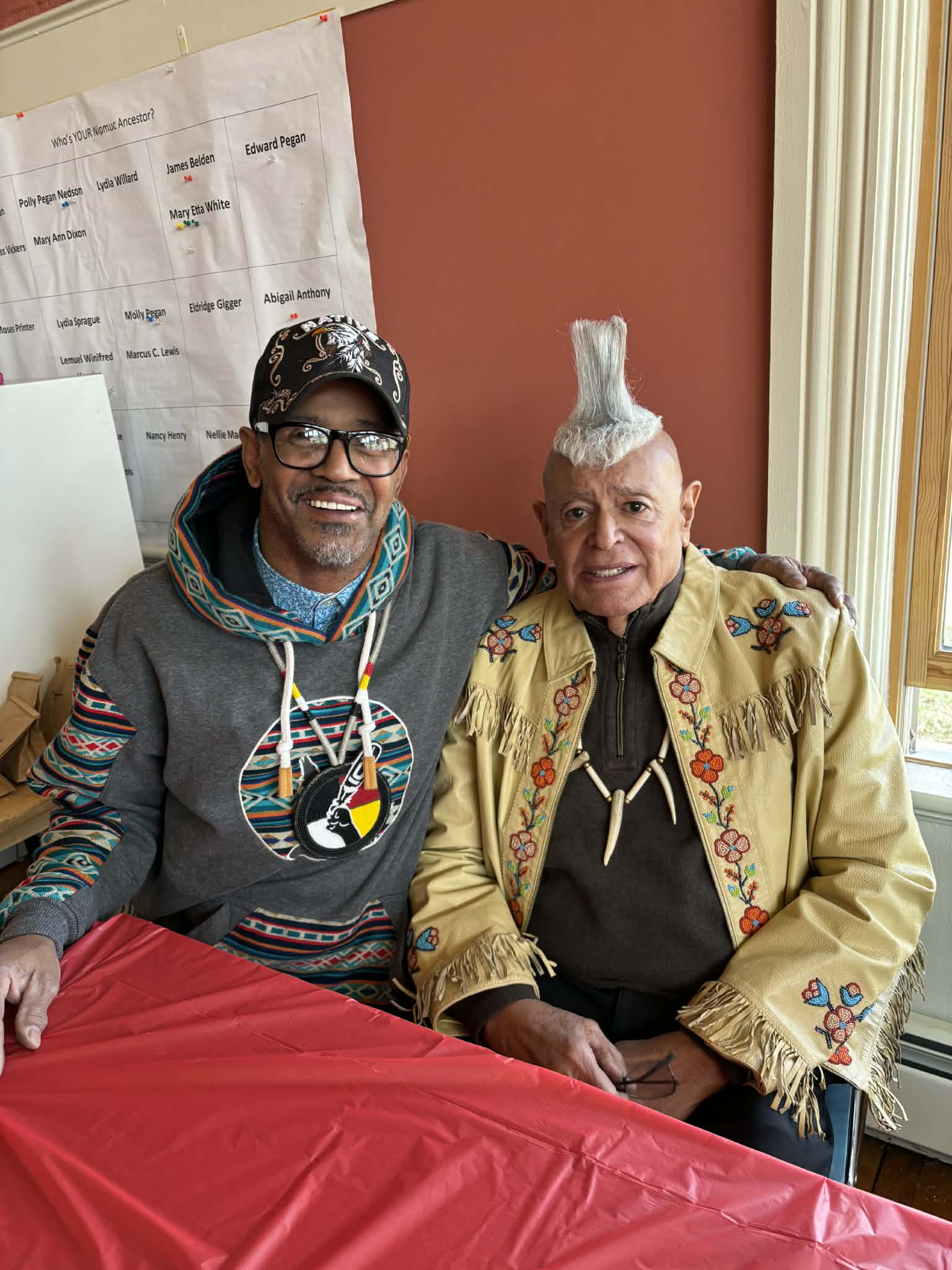 Two men posing beside a Nipmuc ancestor genealogy chart