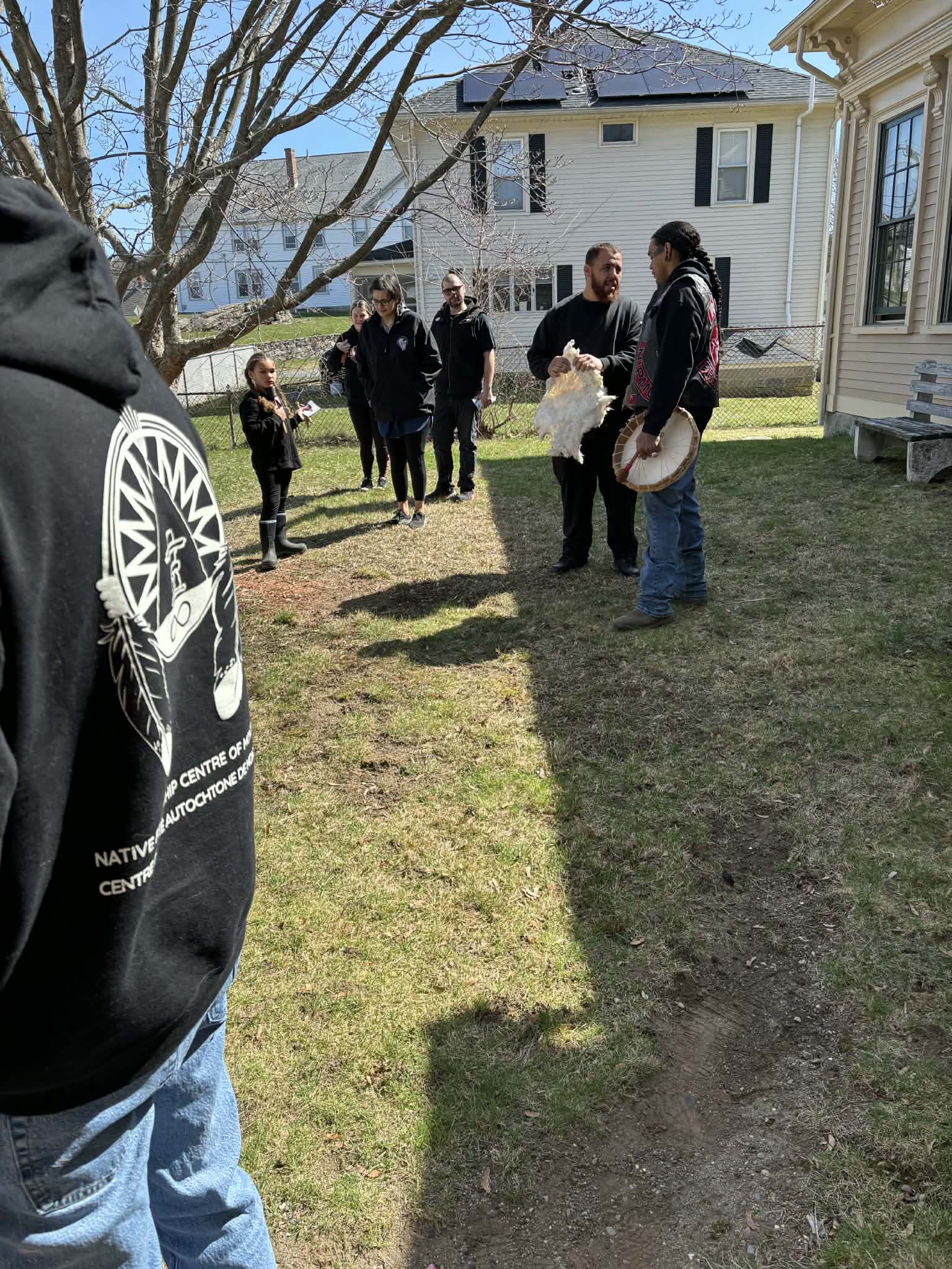 A group gathered outdoors for a hide and drum teaching session