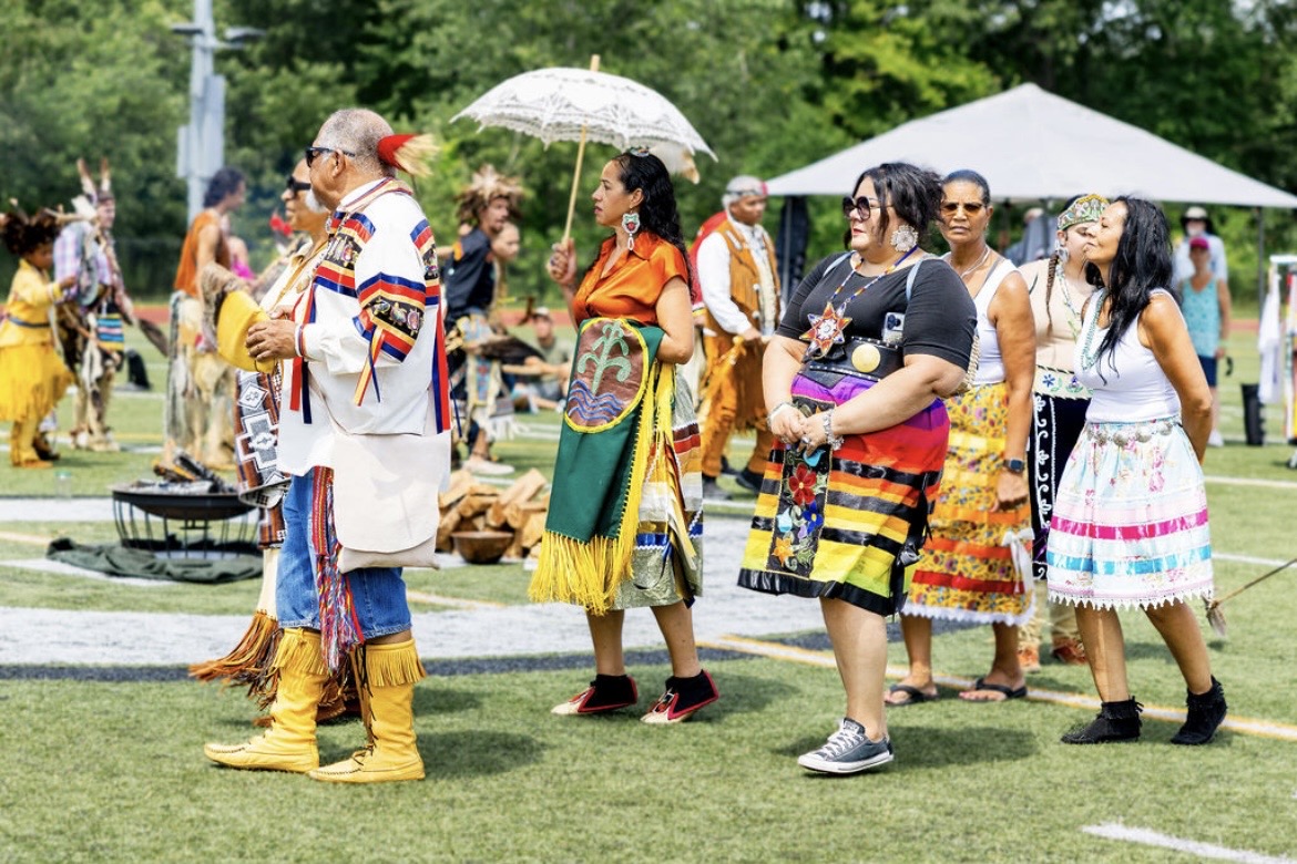 Community members in regalia gathered together at the powwow