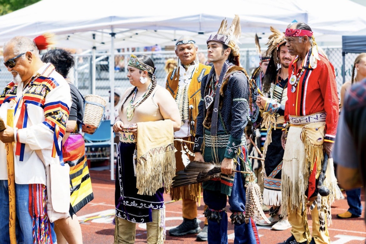 Dancers in regalia lined up together at the powwow