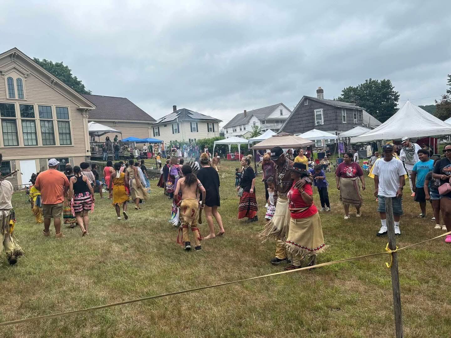 Community members and visitors dancing together at the powwow
