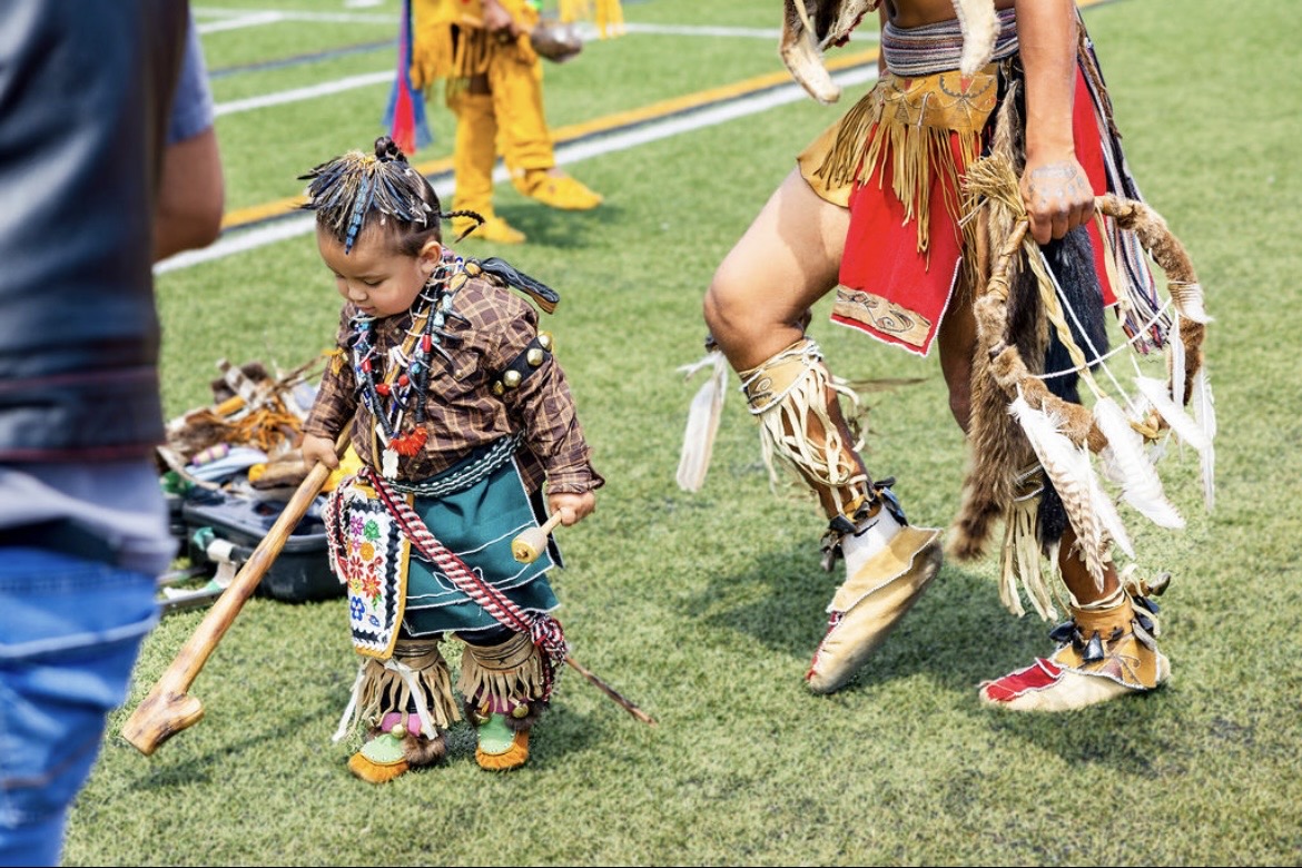 A toddler in regalia dancing at the powwow