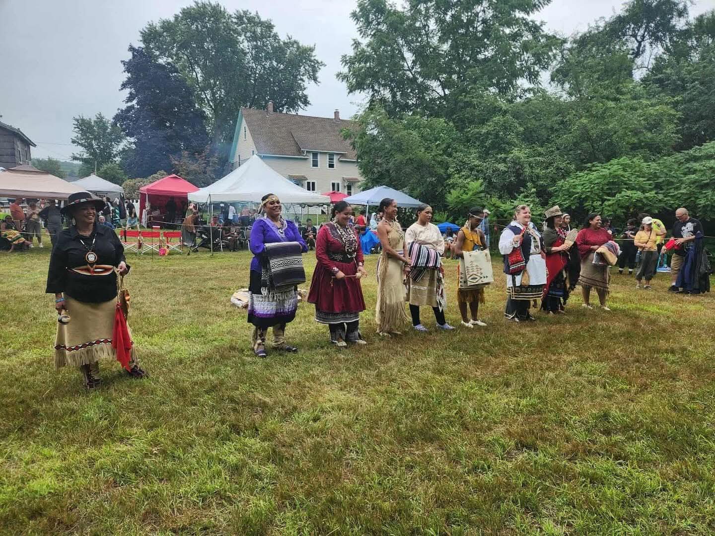 A line of women in regalia at the powwow grounds
