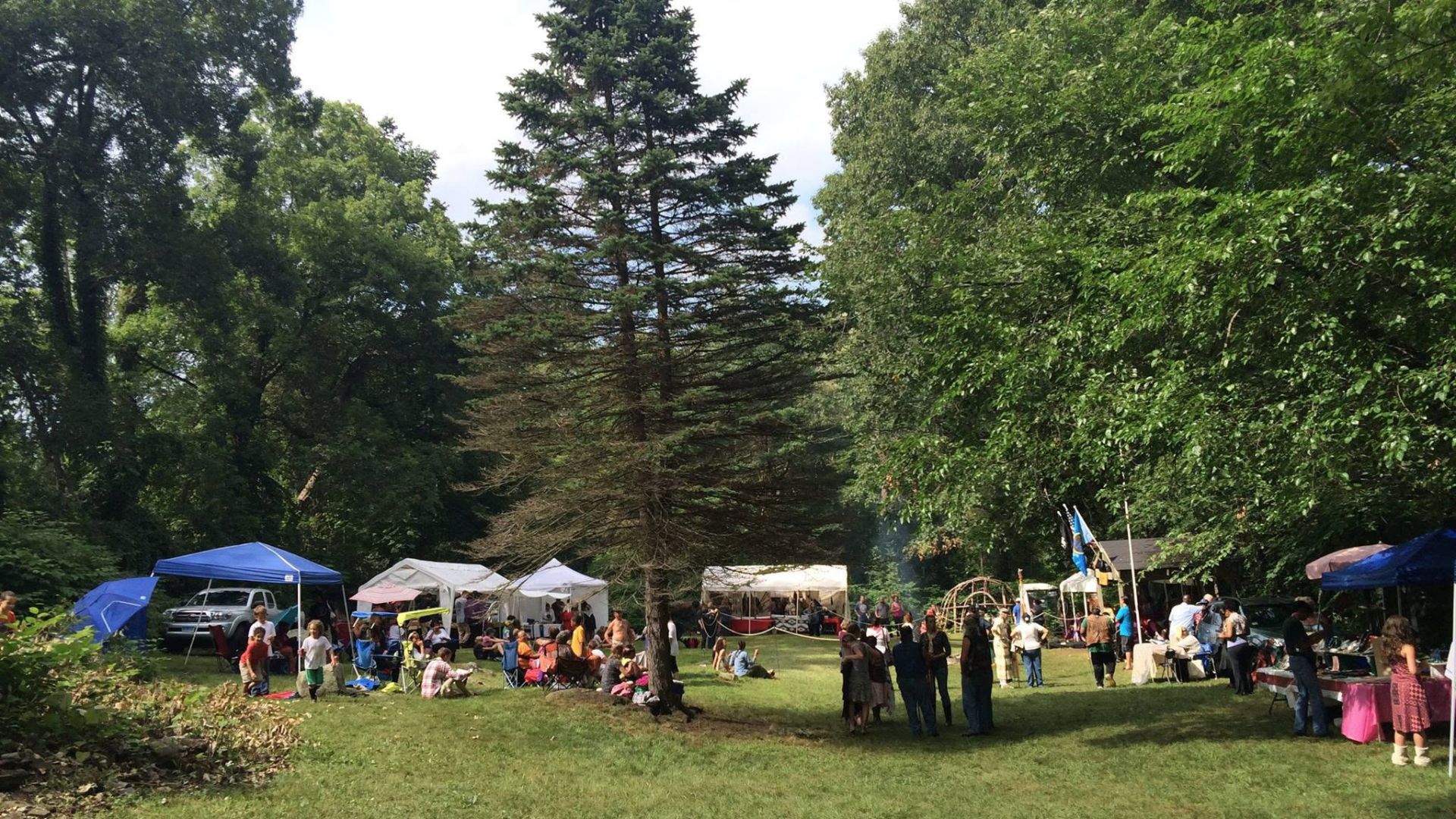 Community gathering with tents and vendor tables on the Hassanamisco Reservation