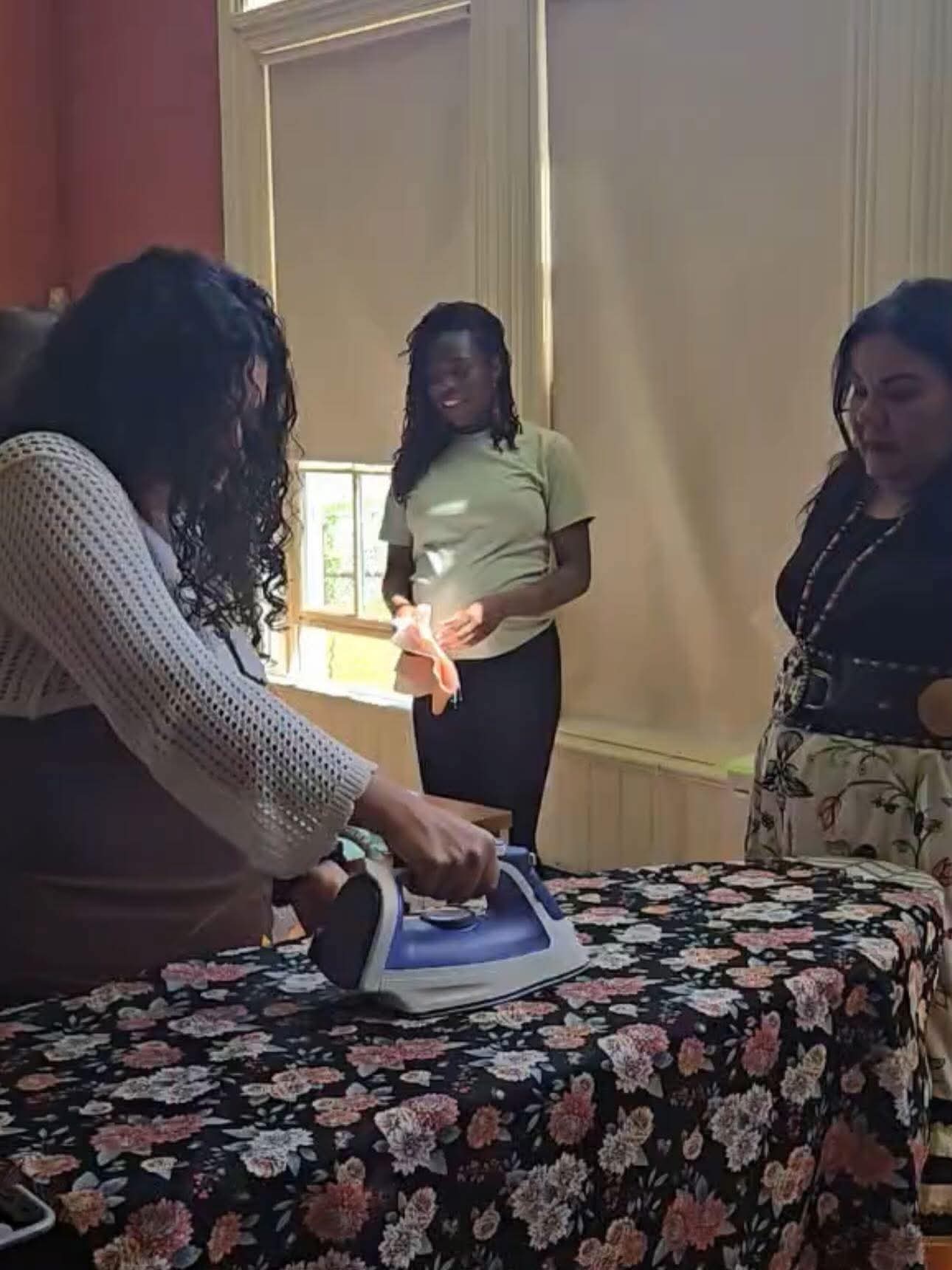 Workshop participant ironing ribbon onto floral fabric
