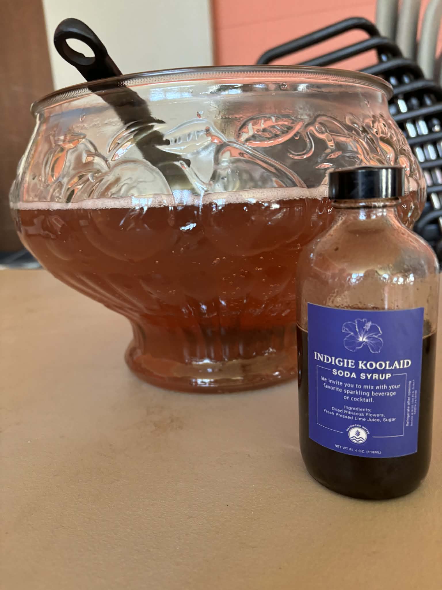 A bottle of Indigie Koolaid soda syrup beside a punch bowl