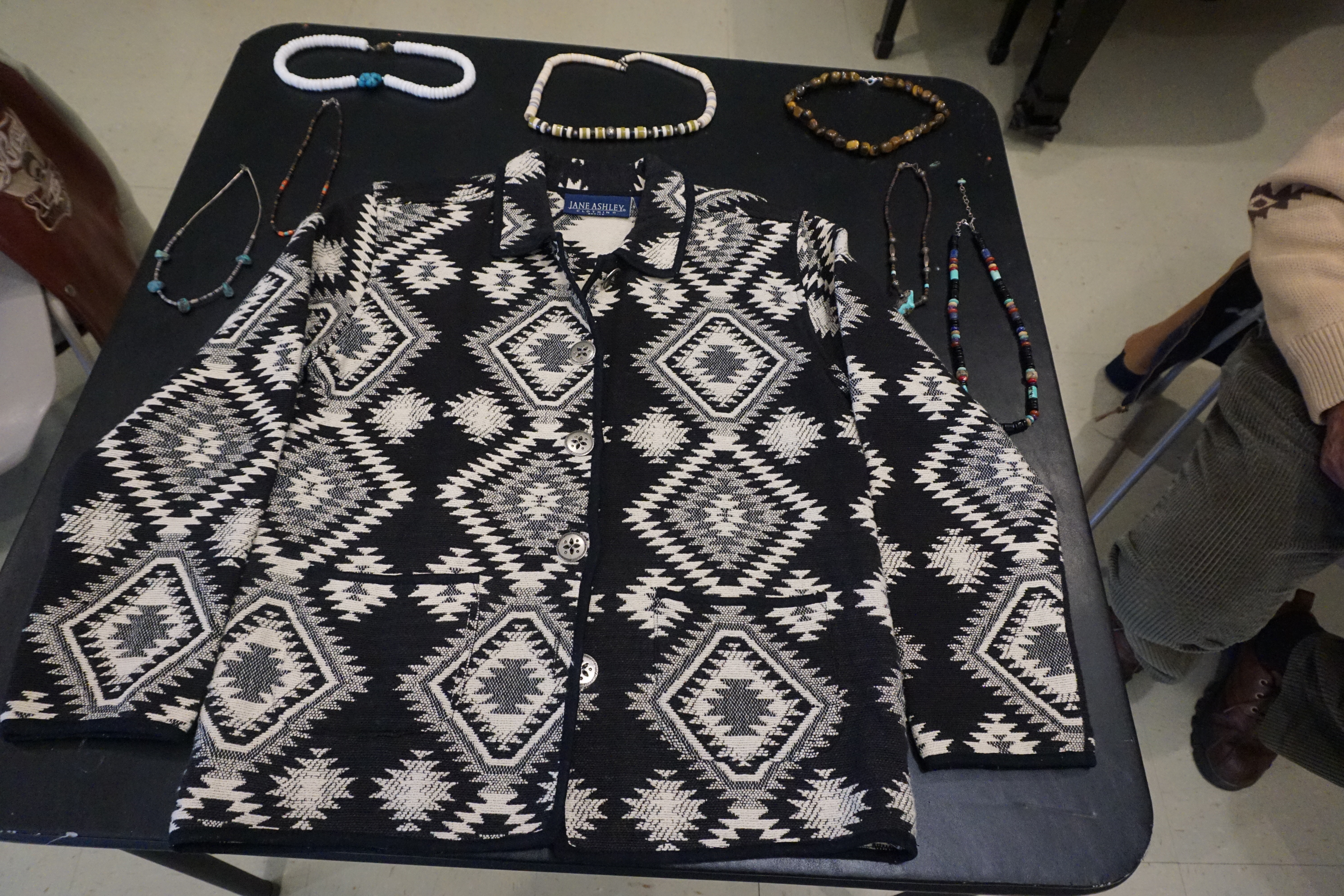 Handmade beaded jewelry and a patterned jacket displayed at the Trade Event