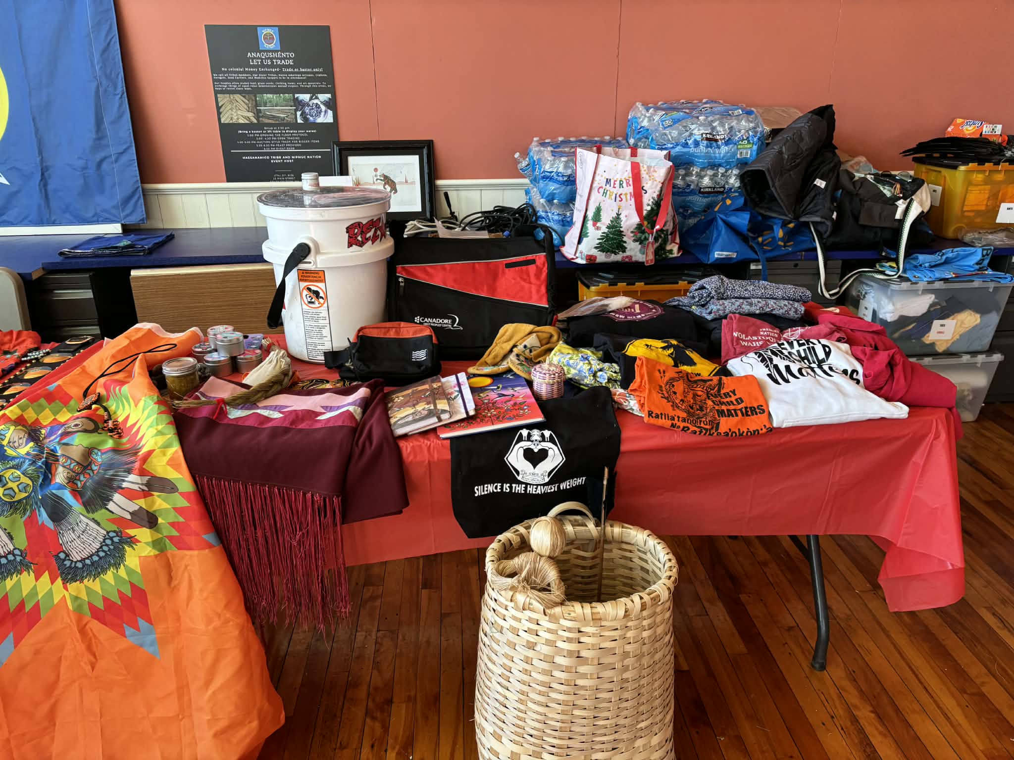 Table of trade goods including regalia, t-shirts, and a woven basket
