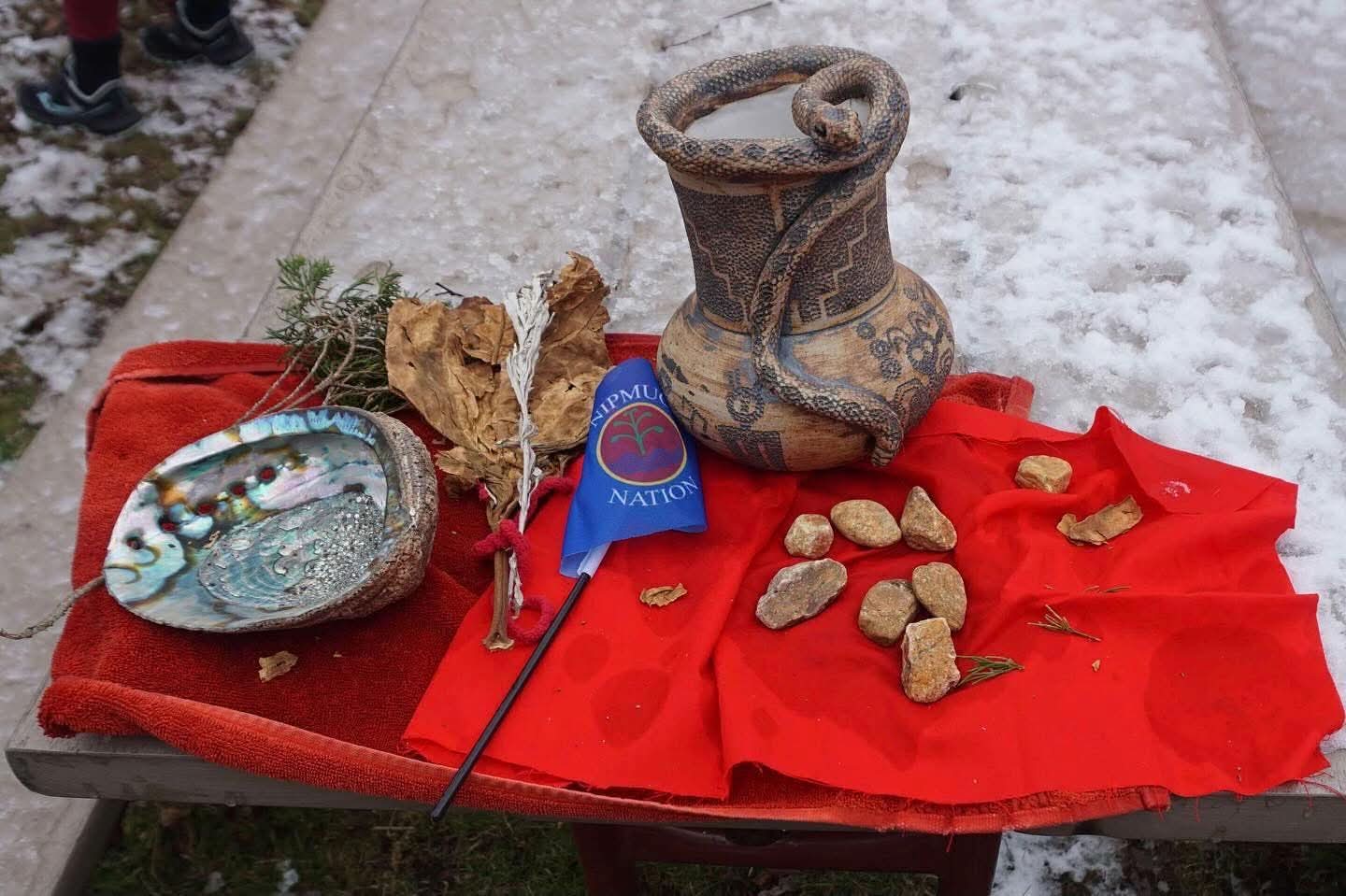 Ceremonial items laid out for the water ceremony, including an abalone shell, sage, tobacco, and a decorated vessel