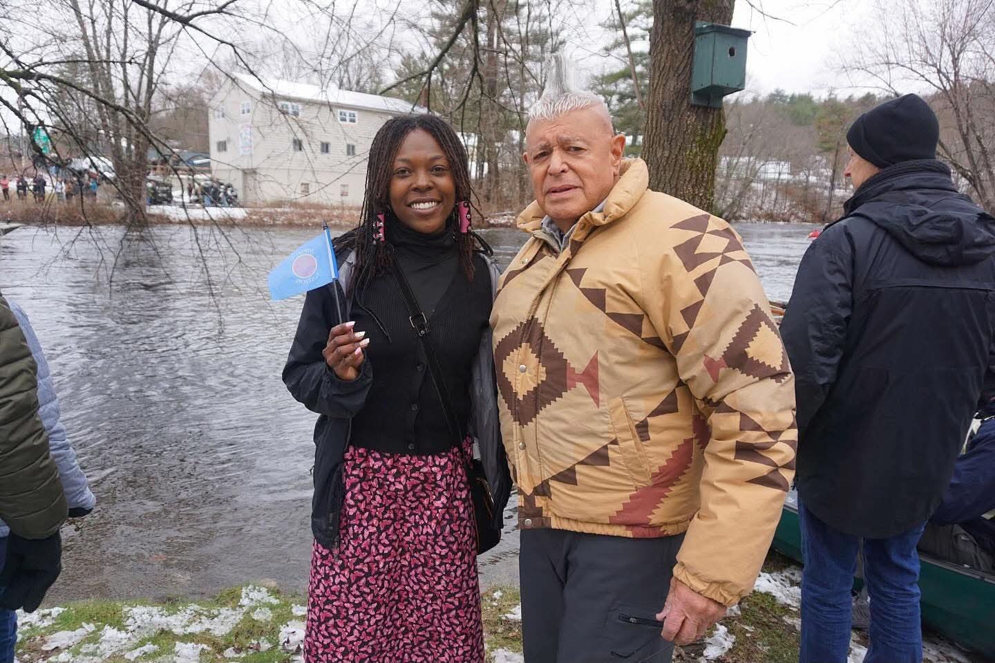 Community members beside the river at the water ceremony, with a canoe nearby